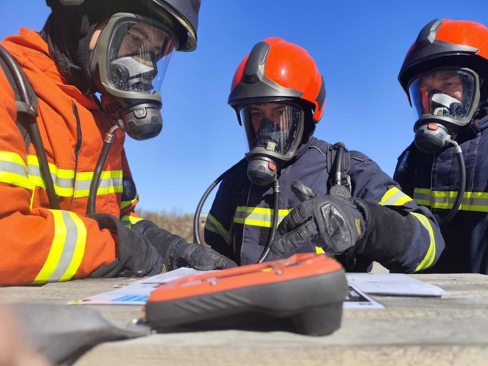 Sapeurs-pompiers sous ARI étudiant un plan de prévention du risque chimique avant la manœuvre